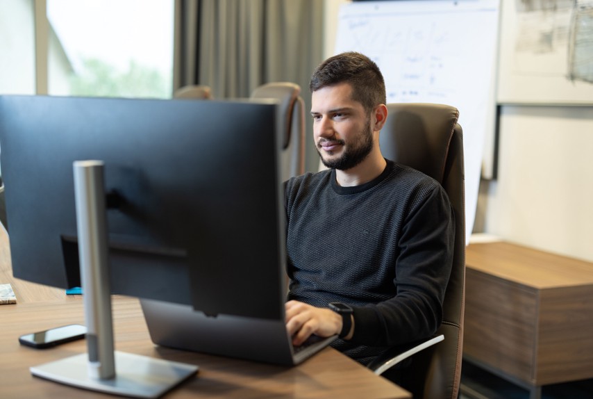 Član tima Aminess Hospitality Groupa radi na računalu u modernom uredu.