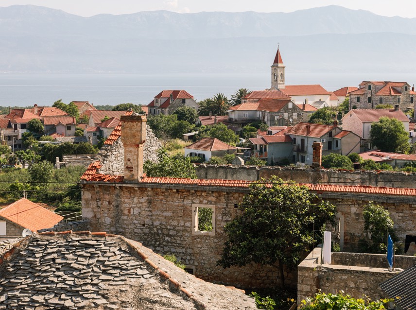 Tradicionalno mediteransko selo na otoku Braču, Hrvatska, s kamenim kućama, uskim ulicama i bujnom zelenilom.