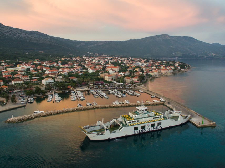 Stunning aerial view of Orebic with a marina, coastal houses, and the Adriatic Sea at sunset in Croatia.