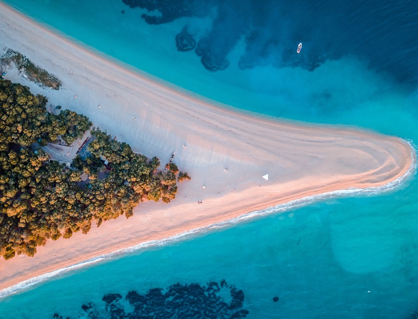 Zlatni Rat Beach on Brač Island, Croatia, featuring a unique golden pebble shoreline, crystal-clear Adriatic waters, and lush pine forest.