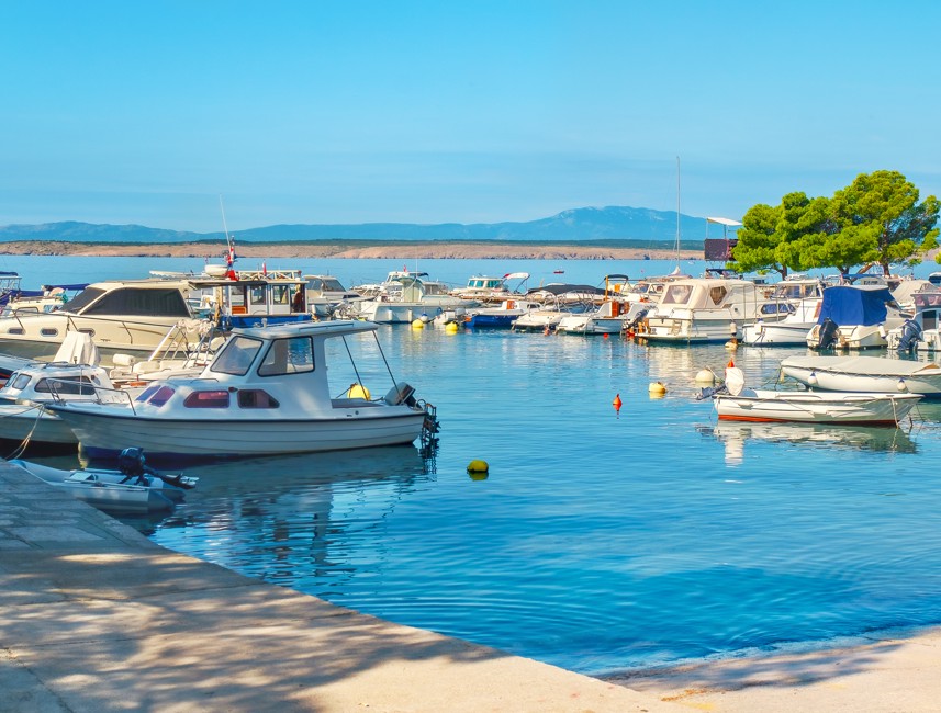 Marina z privezanimi čolni ob mirni obali pod jasnim nebom v Crikvenici.