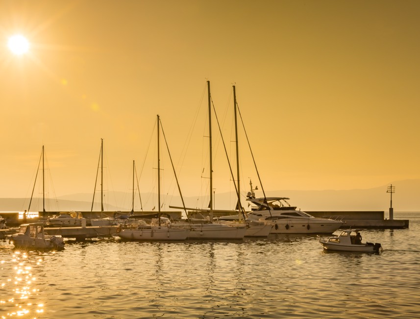 Sunset view of sailboats docked at a marina with golden skies on Krk Island, Croatia.