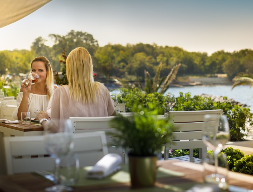 Vrouwen genieten van een glas wijn in een restaurant bij de Aminess Planet Camping Maravea, Novigrad