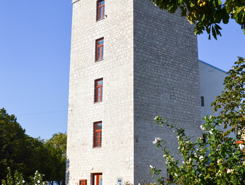 Historic stone tower Kula Turnac in Novi Vinodolski, Croatia, surrounded by greenery.