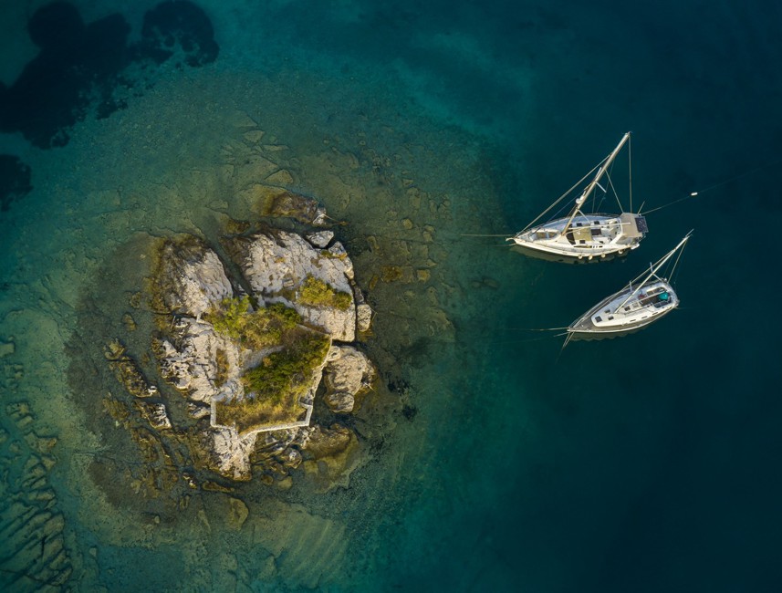 Vista aerea di barche a vela presso un isolotto nel mare limpido di Korčula.