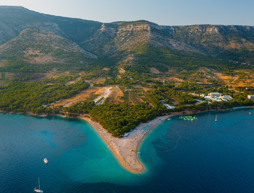 Aerial view of the famous Zlatni Rat Beach in Bol, Brač Island, Croatia, showcasing its unique golden pebble shape and surrounding turquoise waters.