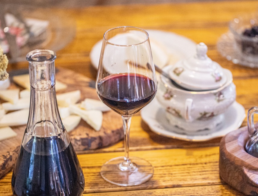 Glasses of red wine on Brač Island, Croatia, placed on a rustic wooden table with a wine bottle.