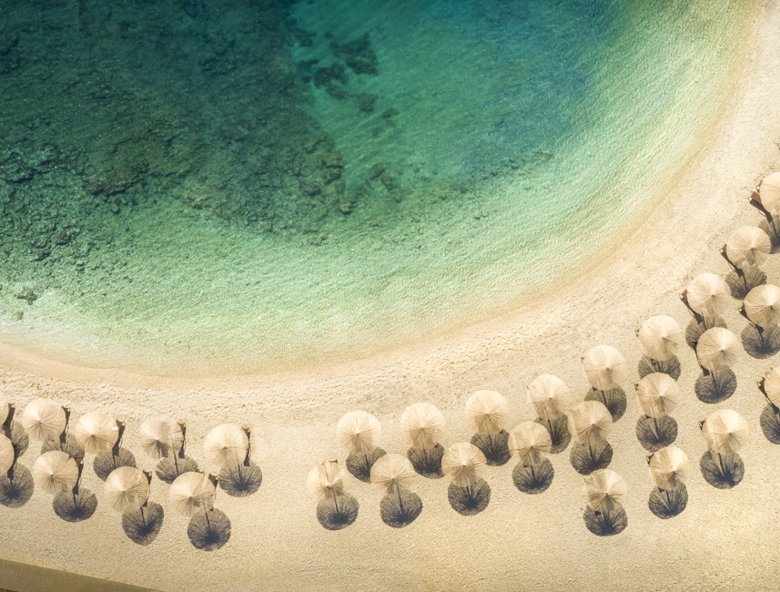 Bildschöne Aussicht auf das Meer mit Sonnenschirmen und Strandliegen.