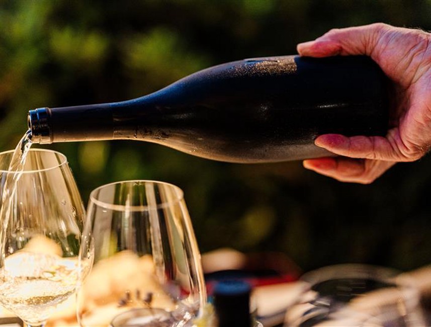 Pouring wine into glasses outdoors as part of the experience of tasting Croatian terroir specialties
