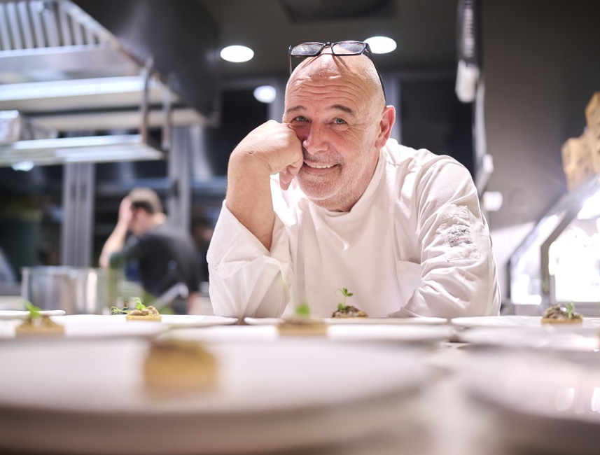 Lo chef Zirojević nella cucina a vista del ristorante rooftop The Above, mentre presenta piatti gourmet moderni in un elegante ambiente Aminess