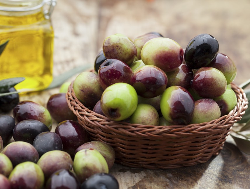 Fresh olives and olive oil in a woven basket, showcasing Krk Island's gastronomic tradition.