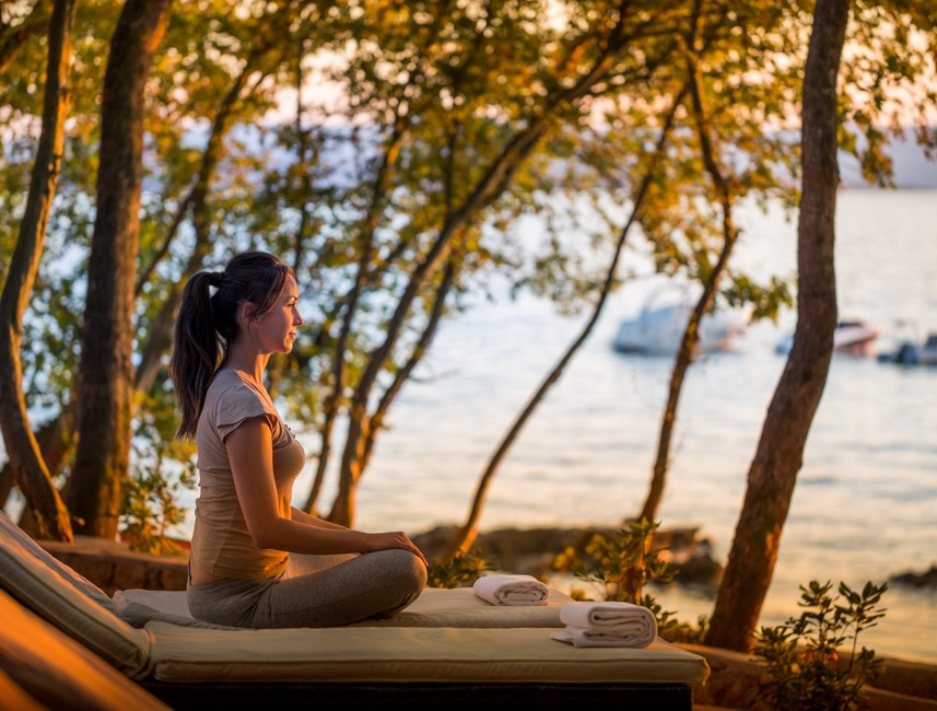 Gast genießt eine friedliche Yoga-Sitzung inmitten der Natur mit Blick auf das Meer im Aminess Style Camping Atea Resort.