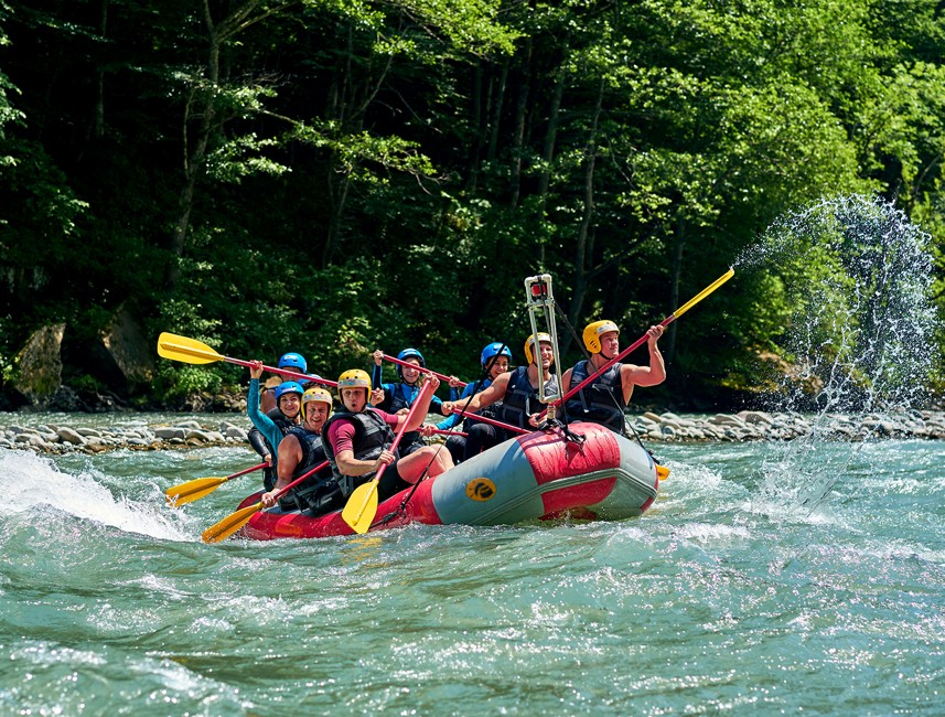 Raftingavontuur op een rivier met een team dat door stroomversnellingen peddelt
