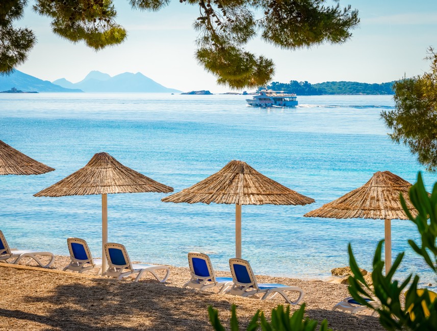 Pogled na plažo s senčniki in ležalniki pred hotelom Aminess Vival Grand Azur, Orebić.