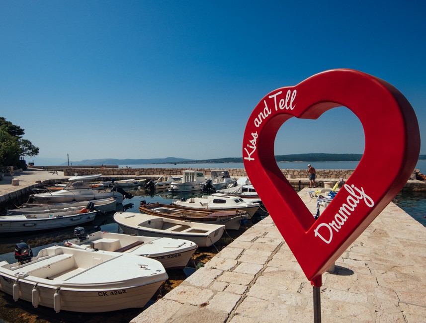 Pier in Dramalj with boats and a heart-shaped photo point installation.