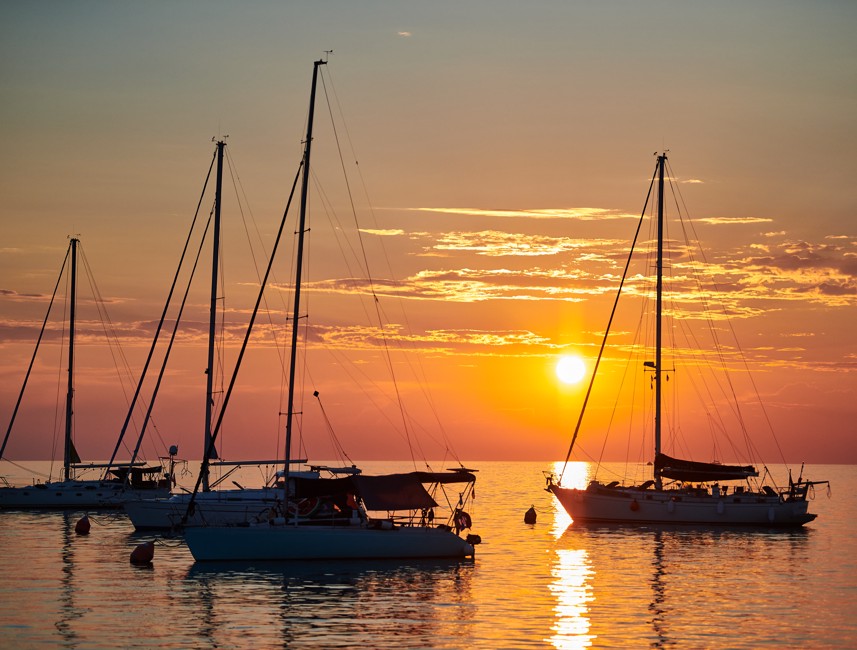Zalazak sunca iza četiri jedrilice na moru