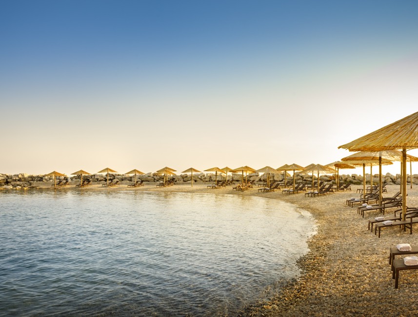 Šljunčana plaža u Novigradu s ležaljkama i suncobranima tijekom zalaska sunca