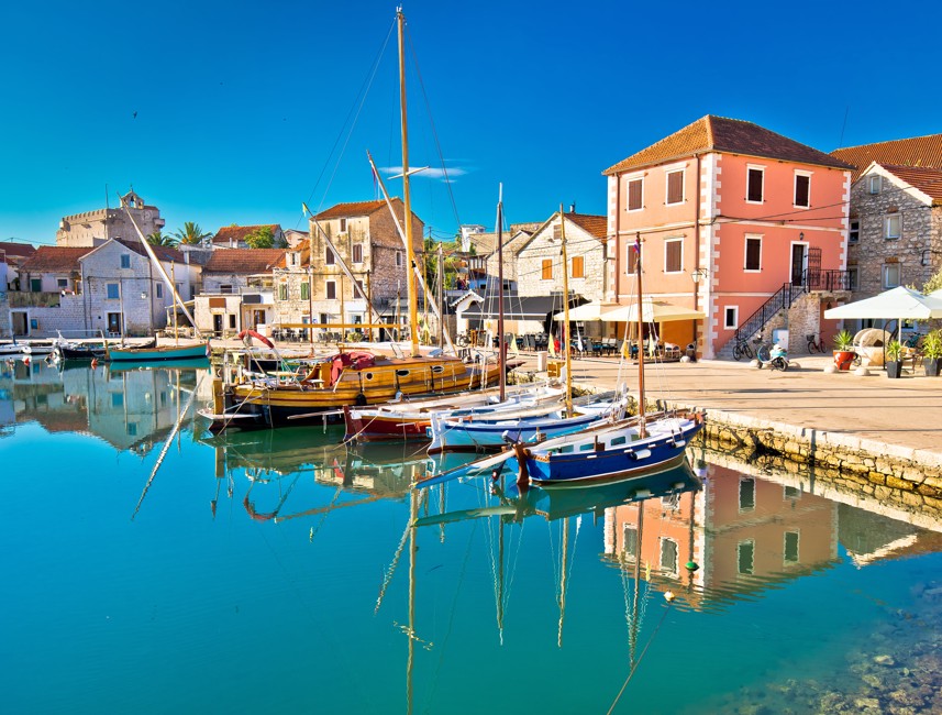 A picturesque view of Vrboska on Hvar Island, Croatia, showcasing charming stone houses, boats in the canal, and lush Mediterranean scenery – Aminess destination travel.