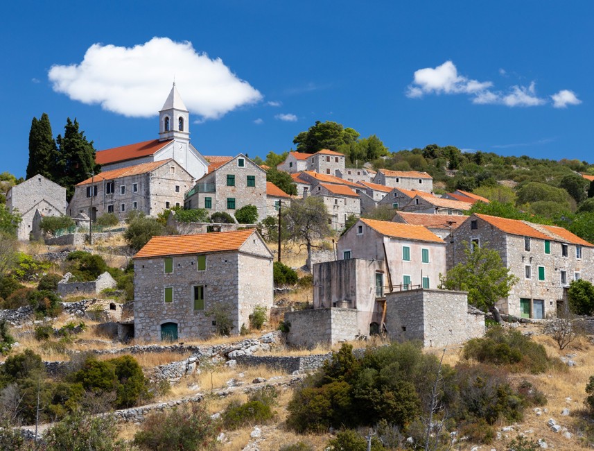 Traditional stone houses in the historic Hum village on Hvar Island, Croatia, surrounded by lush greenery and showcasing authentic Mediterranean architecture – Aminess destination travel.