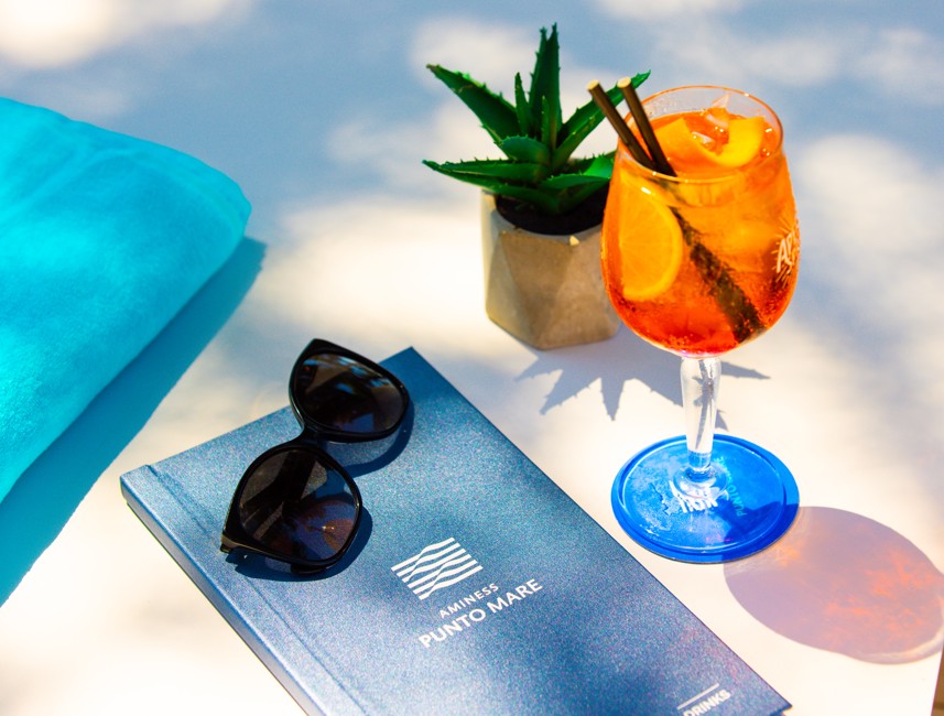 Verfrissende cocktail op tafel met zonnebril en een Aminess Punto Mare menu