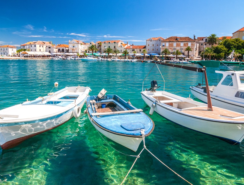Three fishing boats in the foreground with the city and the Adriatic Sea in the background on Brač Island, Croatia, showcasing the island’s coastal charm and maritime heritage.