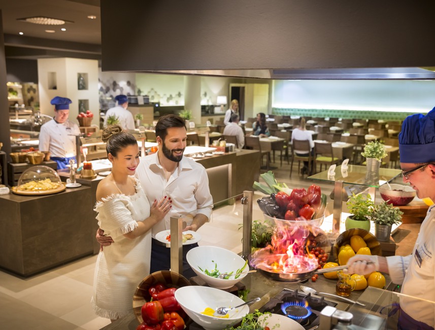 A couple enjoying the live cooking experience at the restaurant.