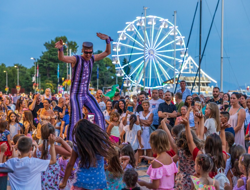 CrikvArt event in Crikvenica featuring a lively crowd, performers, and a Ferris wheel in the background.