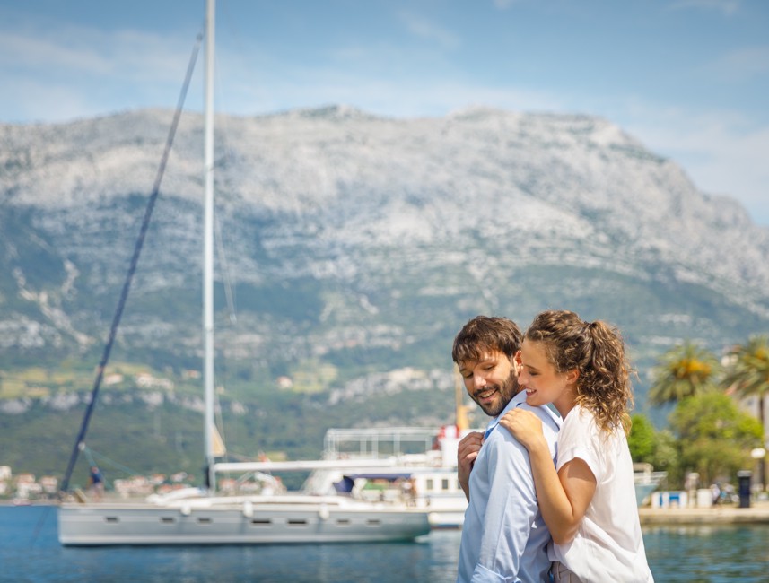 A couple enjoys stunning Adriatic Sea and mountain views near a luxury yacht on Korcula Island.