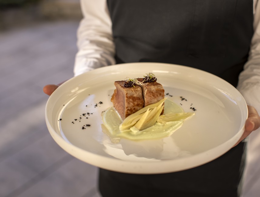 Waiter presenting a gourmet dish at 7 Seas Restaurant in Korcula, featuring seared tuna steak served on a bed of creamy sauce.