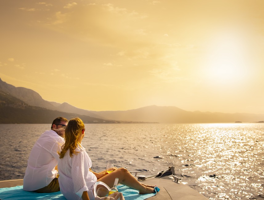 Couple relaxes on a sailboat at sunset, experiencing a peaceful Adriatic getaway on Korcula Island.