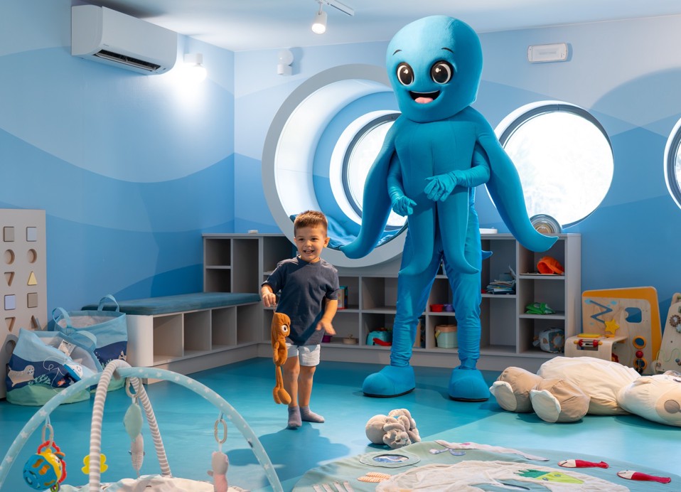 Bambino gioca con una mascotte nella sala giochi dell Aminess Khalani Hotel.