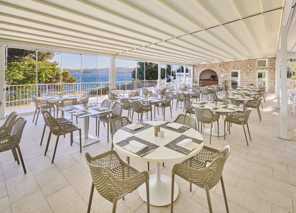 Elegant outdoor dining setup at Restaurant Rondela, offering a relaxing view of the Adriatic coastline and lush greenery at Aminess Maradiso Casa Bellevue.