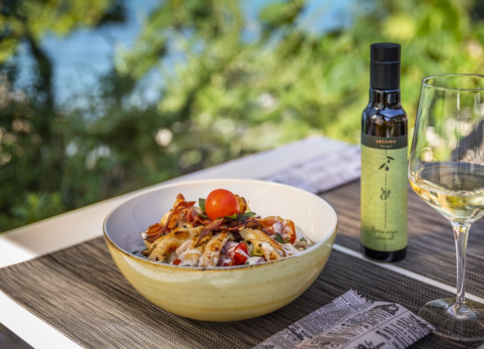 Schüssel mit Pasta, Kirschtomaten und Parmesan, serviert im Il Cantuccio Restaurant innerhalb des Resorts, in der Nähe von Aminess Vival Port9 Residence, Korcula, begleitet von Wein und Olivenöl.