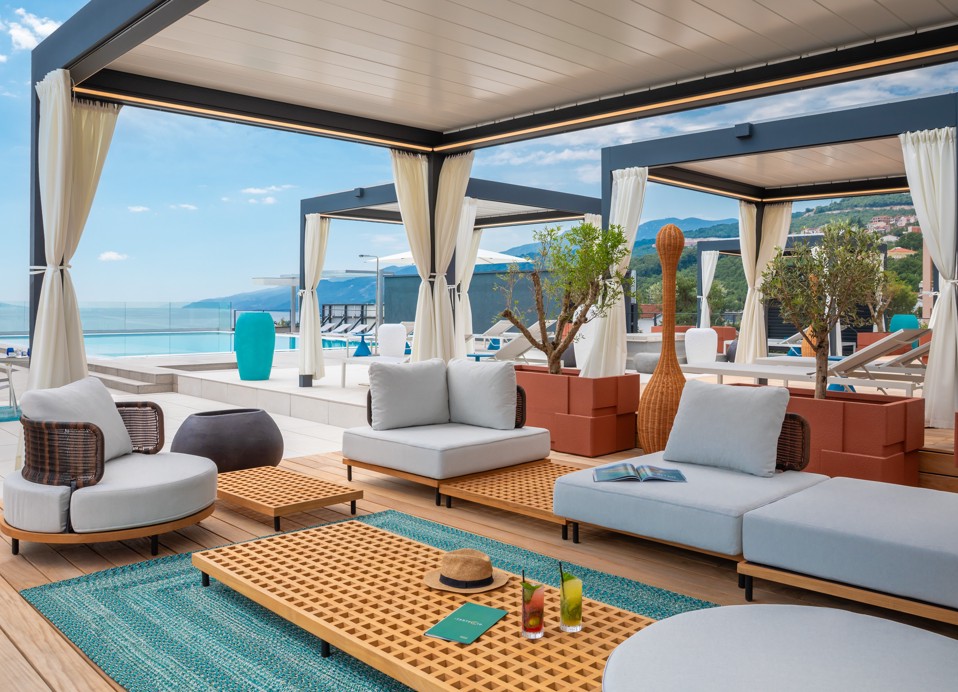 Poolside lounge with cabanas, sofas and a sea view