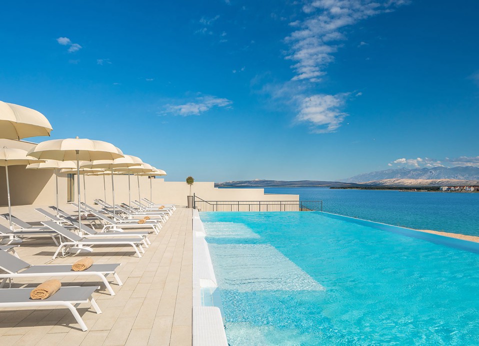 Ligstoelen en parasols opgesteld naast het relax zwembad met zeezicht bij Aminess Style Camping Avalona resort.