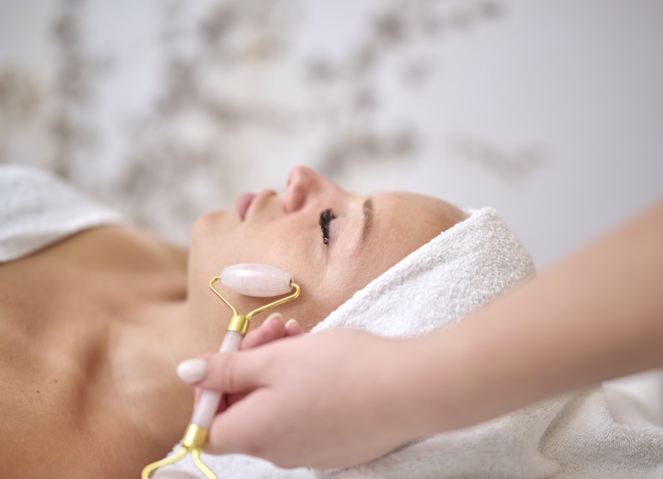 Ontspannende spa-behandeling met een gezichtsroller bij Aminess Style Camping Atea Resort, huidverjonging bevorderen in een serene omgeving.