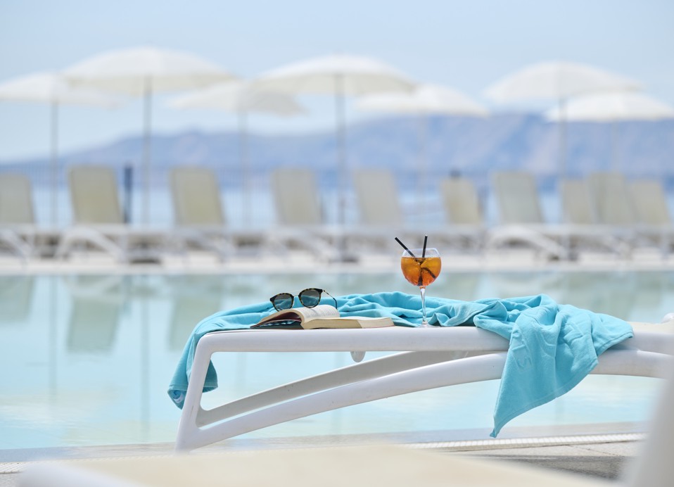 Liegestühle am Pool mit Handtüchern, Sonnenbrillen und erfrischendem Cocktail im Hotel Aminess Lišanj.
