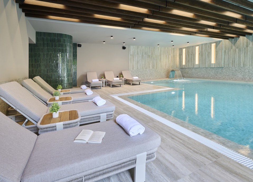 Basen wewnętrzny w hotelowej strefie wellness z leżakami do relaksu