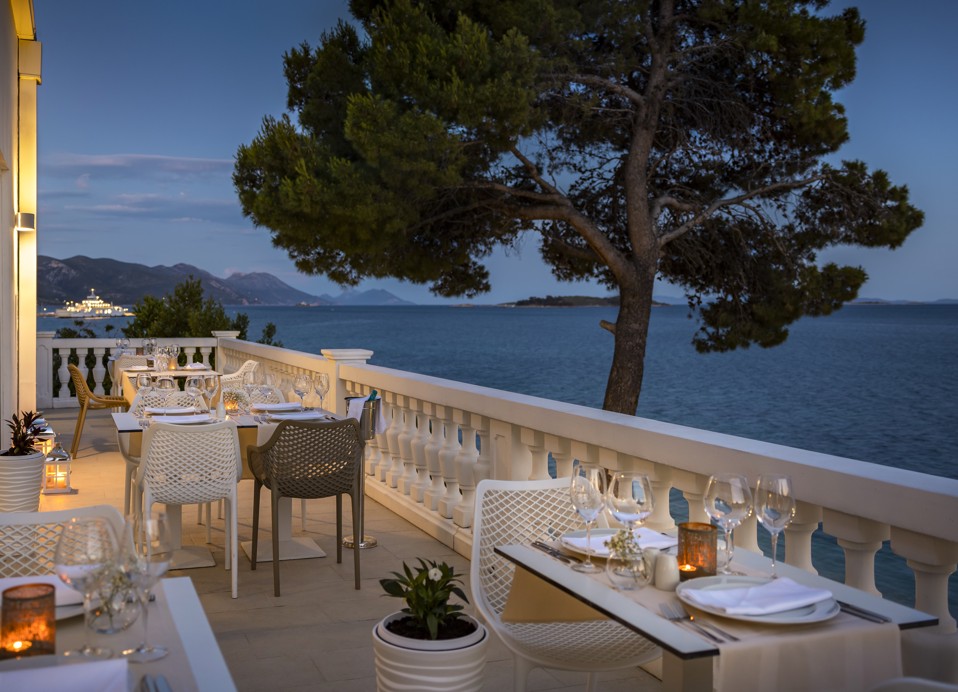 Unique seaside restaurant table seating at the at Aminess Younique Bellevue Hotel terrace, featuring white modern chairs and a romantic table set up.