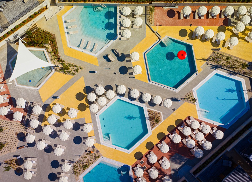 Bovenaanzicht van zeshoekige zwembaden, ligstoelen en parasols in een geometrische indeling in Aminess Style Camping Atea Resort.