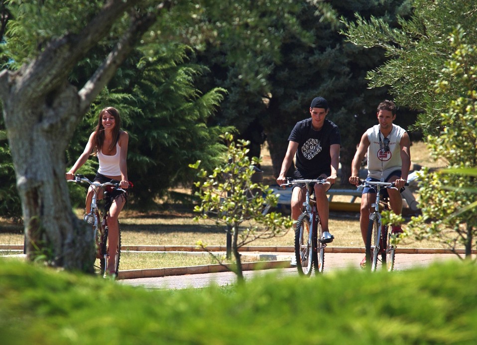 Three cyclists ride through a green park near Karlovac.