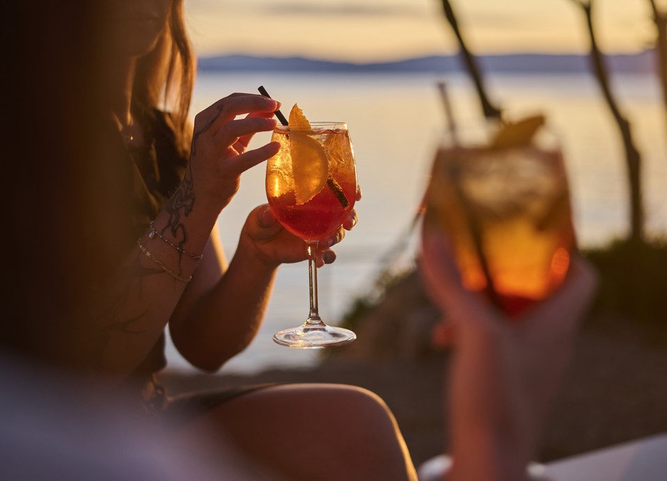 Približan posnetek koktajla v roki v lounge baru Punto Mare ob sončnem zahodu