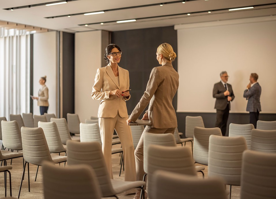 Two women are talking in a congress hall at Aminess Laurel Khalani hotel.