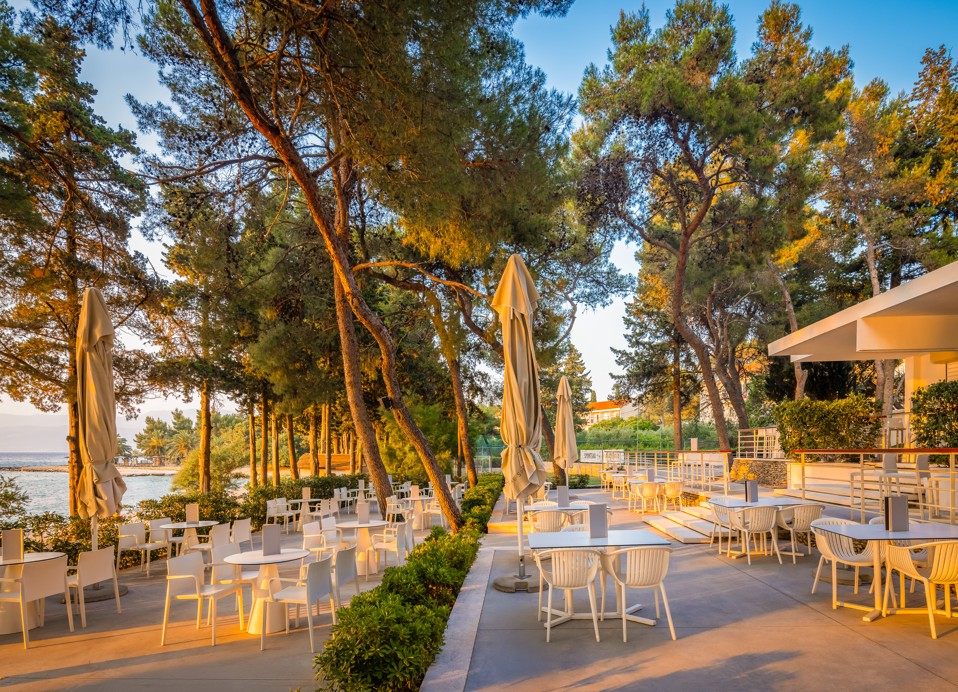 Terasni del restavracije Punto Mare v letovišču Aminess Vival Velaris na Braču, obdan z borovci ob morju