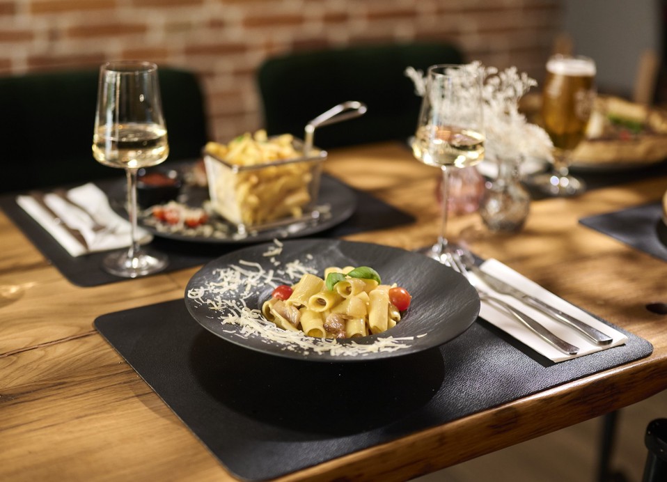 Pasta with sauce, tomatoes and basil beside white wine at Aminess Kadoor Hotel.