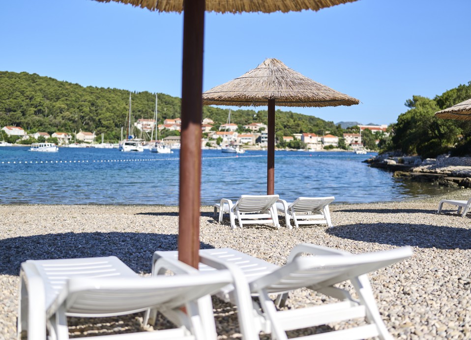 Sonnenliegen am Kieselstrand, mit einem Panoramablick auf das Meer im Aminess Vival Port9 Resort in Korcula.