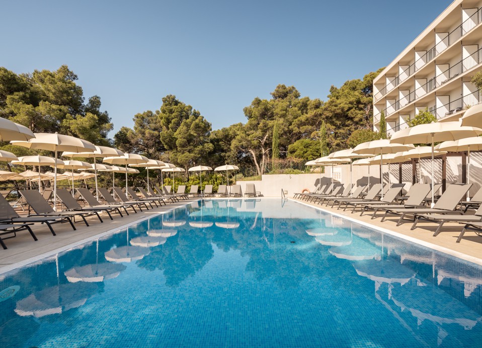 Outdoor pool with sun loungers and umbrellas at Aminess Younique Senses Resort on Hvar Island