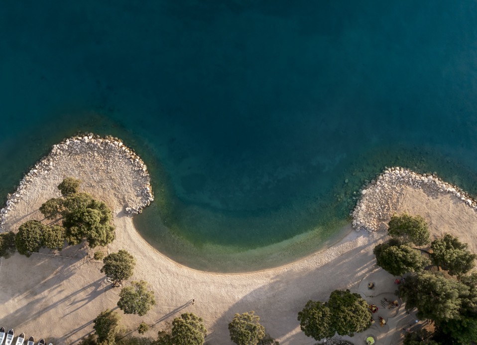 Vista aerea di una spiaggia di ciottoli appartata vicino all'Aminess Younique Narrivi Hotel.