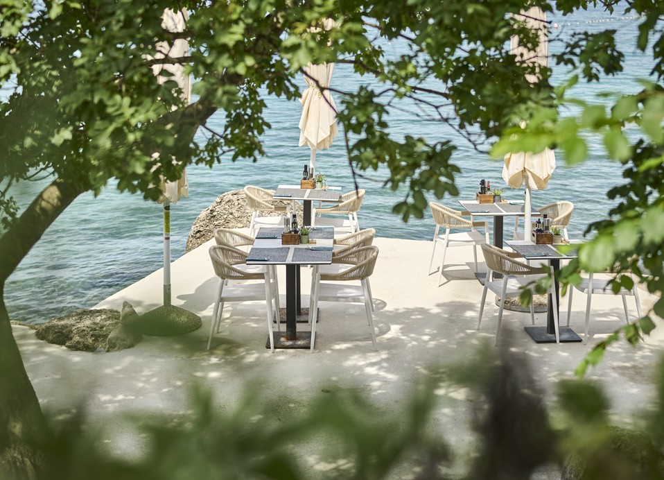 Zunanje jedilno območje s pogledom na morje, obdano z zelenjem pri Il Cantuccio blizu Aminess Style Camping Atea Resort.