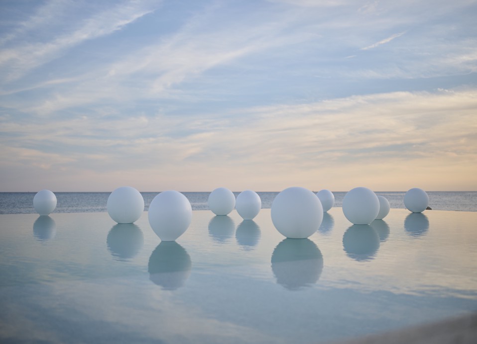 The image shows an outdoor pool decorated with white floating balloons.